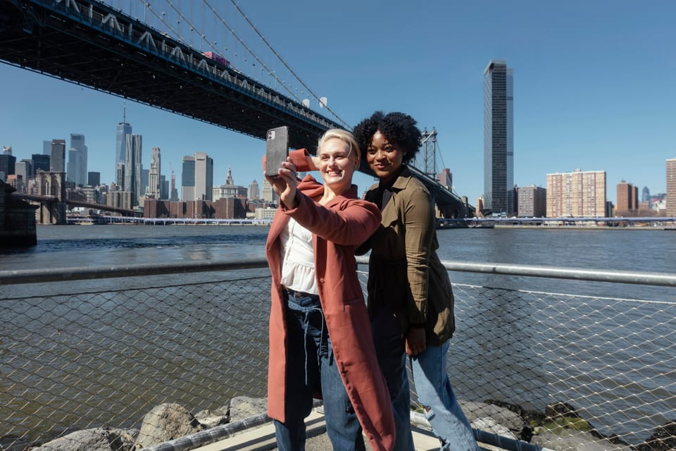 Three friends smiling together for a selfie by the waterfront