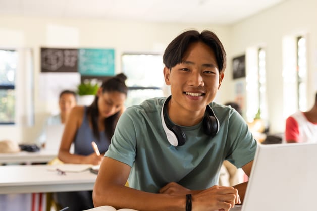 A student smiling while learning with headphones