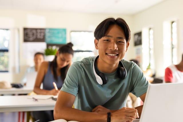 A smiling high-school student wearing headphones