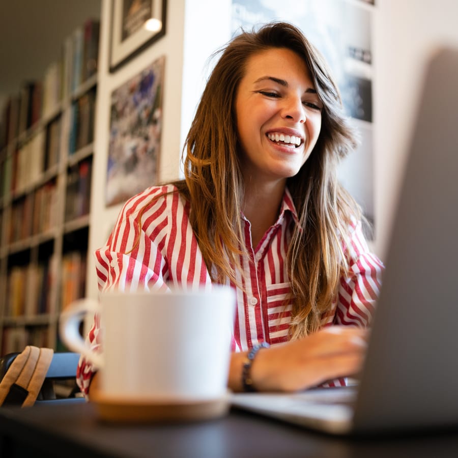 A smiling woman working on a laptop at home